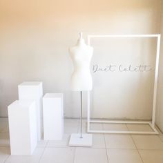 a white mannequin sitting on top of a table next to three cubes