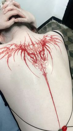 the back of a woman's shoulder with blood splattered on her body