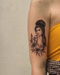 a woman's arm with a flower and lady tattoo on the left side of her arm