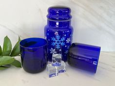 three blue glass containers and two glasses on a table