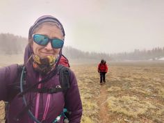 a woman hiking in the foggy mountains with her backpack and goggles over her face