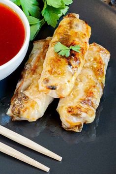 some food is sitting on a plate with chopsticks next to it and sauce