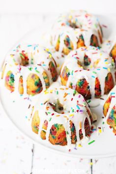 a white plate topped with bundt cakes covered in frosting and sprinkles