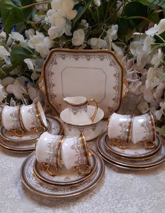 a white and gold dinner set with flowers in the background