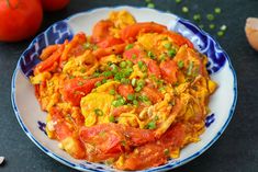 a plate full of food on a table next to tomatoes and garlic, along with other vegetables