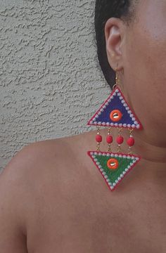 Enhance your outfit with the luxurious Harmony Crystal Triangle Earrings. The top and bottom mismatched design in vibrant green and blue is accented with red handmade clay beads, champagne glass crystals and amazonite semiprecious stones. Adorned with vibrant colors and a mirrored detail, these lightweight fabric earrings are wearable work of art. Item Details: Handmade Length: 5.5 Inches; Width: 2.5 Inches Closure: Ear wire; 18k gold plated & nickel free Materials: Polyester, Clay Beads, Glass Crystals Colors: blue, green, red, orange, white, silver, champagne, and gold Unique Green Beaded Earrings For Party, Bohemian Jeweled Beaded Earrings For Gifts, Unique Green Beaded Party Earrings, Unique Multicolor Beaded Earrings For Party, Unique Multicolor Earrings For Celebration, Festive Green Earrings With Colorful Beads, Vibrant Handmade Green Jewelry, Green Dangling Beads Earrings For Celebration, Green Beaded Earrings With Dangling Beads For Celebrations