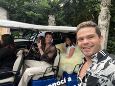 a group of people sitting in the back of a blue and white car with one man smiling at the camera