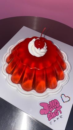 there is a jelly cake on top of the paper with whipped cream and cherry topping