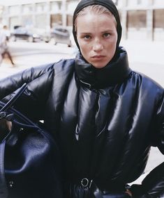 a woman wearing a black coat and holding a handbag