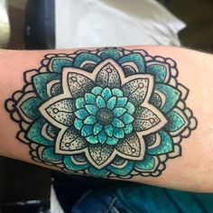 a person with a tattoo on their arm that has a blue and green flower in it