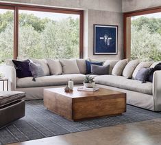 a living room filled with furniture and lots of windows overlooking the trees in the distance