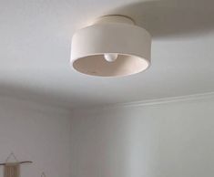 a bedroom with white walls and a round light fixture