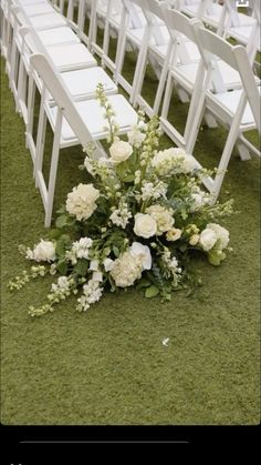 a bouquet of white flowers sitting on top of a grass covered floor next to chairs