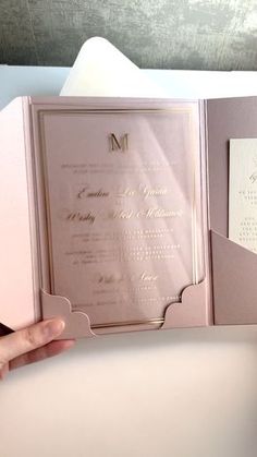 the inside of a pink wedding card with gold foil on it, held in someone's hand