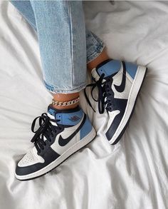 a pair of blue and white sneakers sitting on top of a bed