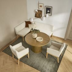 a living room with white couches and chairs around a round wooden table on a rug