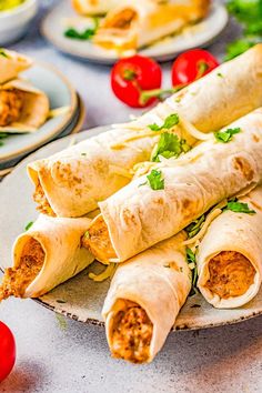 several burritos on plates with tomatoes and lettuce