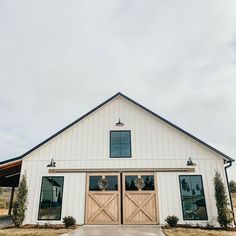 a large white barn with two doors and windows