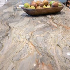 a bowl of fruit sitting on top of a marble counter