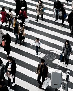 many people are walking across the crosswalk