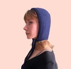 a woman wearing a blue knitted hat on top of her head and looking off to the side