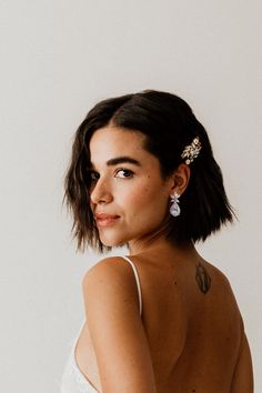 a woman in a white dress with her back turned to the camera and wearing earrings