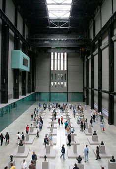 a large room with lots of people walking around and sitting on benches in the middle