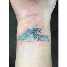 a blue wave tattoo on the wrist is shown in front of a person's hand