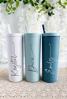 three different colored tumblers with writing on them and one has a straw in it