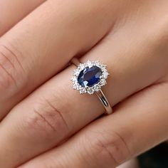 a woman's hand with a blue and white diamond ring on her left hand