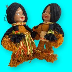 two dolls dressed in native american clothing on a blue background, one is wearing a headdress and the other has dreadlocks