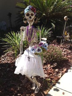 a skeleton in a white dress with flowers on it's head and necklaces around its neck