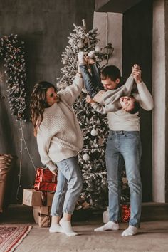 three people standing in front of a christmas tree