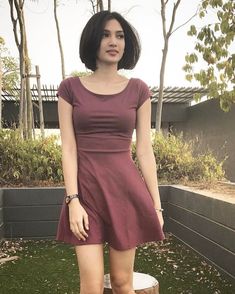 a woman standing on top of a tree stump wearing a dress and high heeled boots