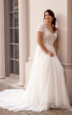 a woman in a wedding dress leaning against a wall