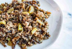 a white plate topped with wild rice and veggies on top of a table