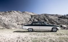 an old black and white car parked in the desert