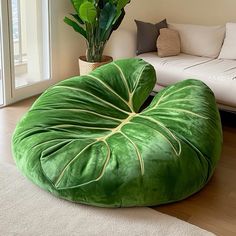 a green bean bag chair sitting on top of a wooden floor next to a white couch