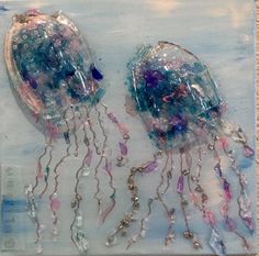 two jellyfishs are sitting on a blue and white background with beads hanging from them