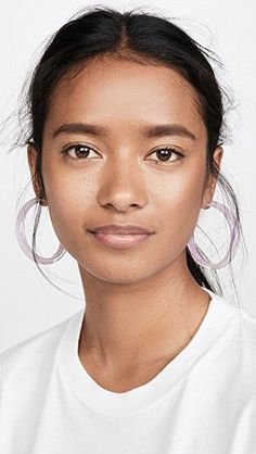 a close up of a person wearing large hoop earrings and a white t - shirt