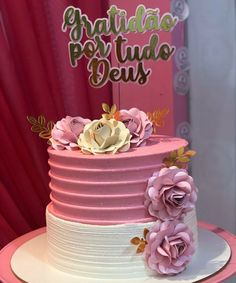 a pink and white cake with flowers on top that says congratulations po tudo deus