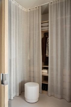 a white stool sitting in front of a curtained closet