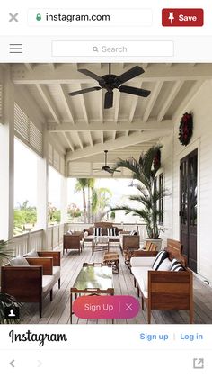 an outdoor covered porch with wicker furniture and plants on the side wall, surrounded by palm trees