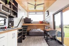 the interior of a tiny home with wood flooring and white walls, along with open windows