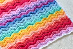 a multicolored crocheted blanket sitting on top of a bed