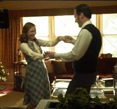 a man and woman dancing in front of a christmas tree