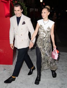 a man and woman holding hands while walking