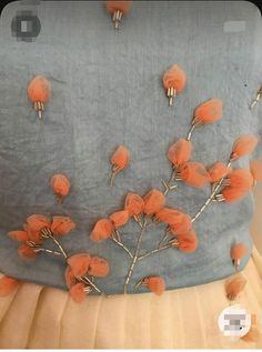 a blue dress with orange flowers on it and pins attached to the back of it