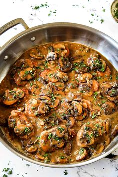 a pan filled with mushrooms and sauce on top of a table