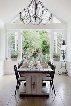 a dining room table is set with place settings and flowers in vases on either side